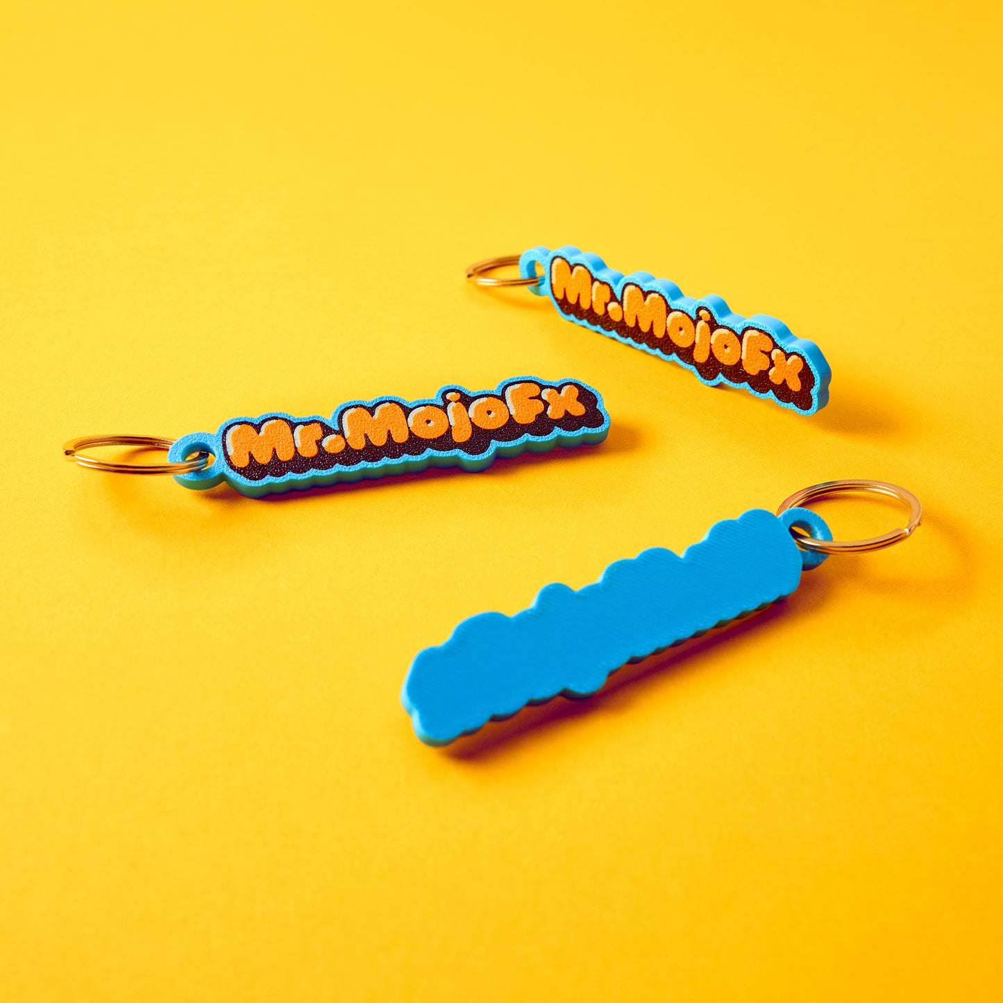 Mr.MojoFx Classic Key Fob — front and back view on yellow background