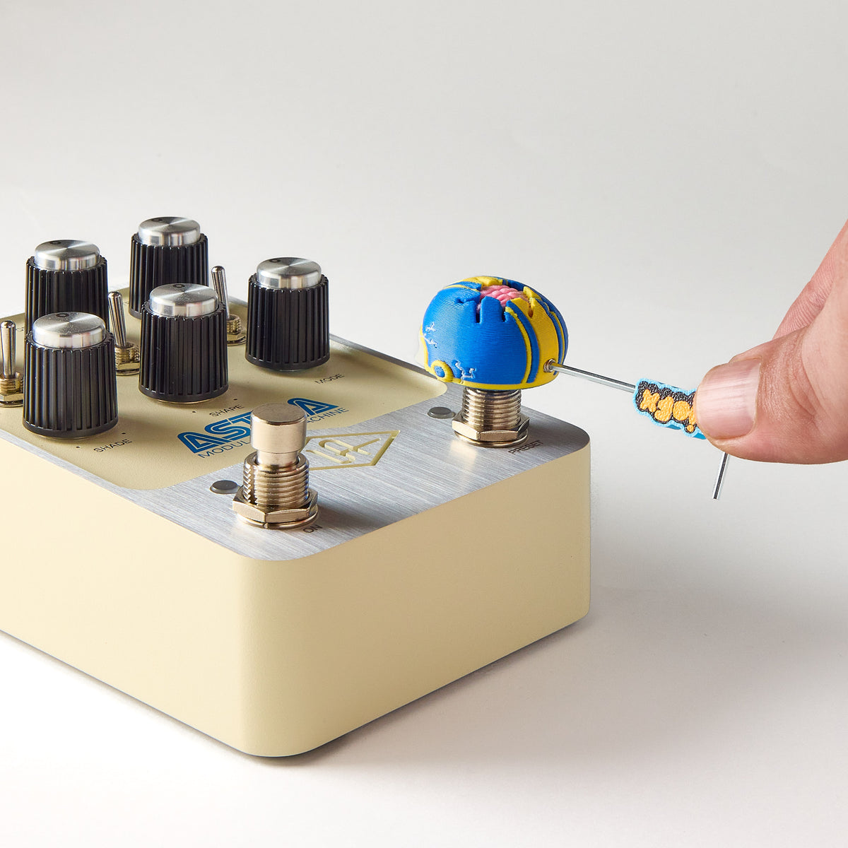 Installing a Mr.MojoFx Dogtown Skull Helmet switch topper onto a cream Universal Audio Astra guitar effects pedal using the 1.5mm Allen key