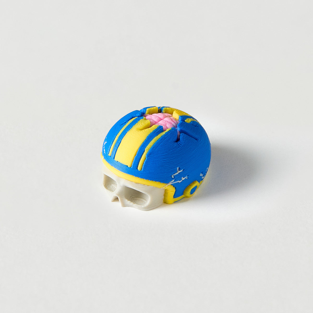 Mr.MojoFX Dogtown Skull Helmet guitar pedal switch topper – white skull wearing a cracked blue skate helmet with yellow stripes and a pink brains