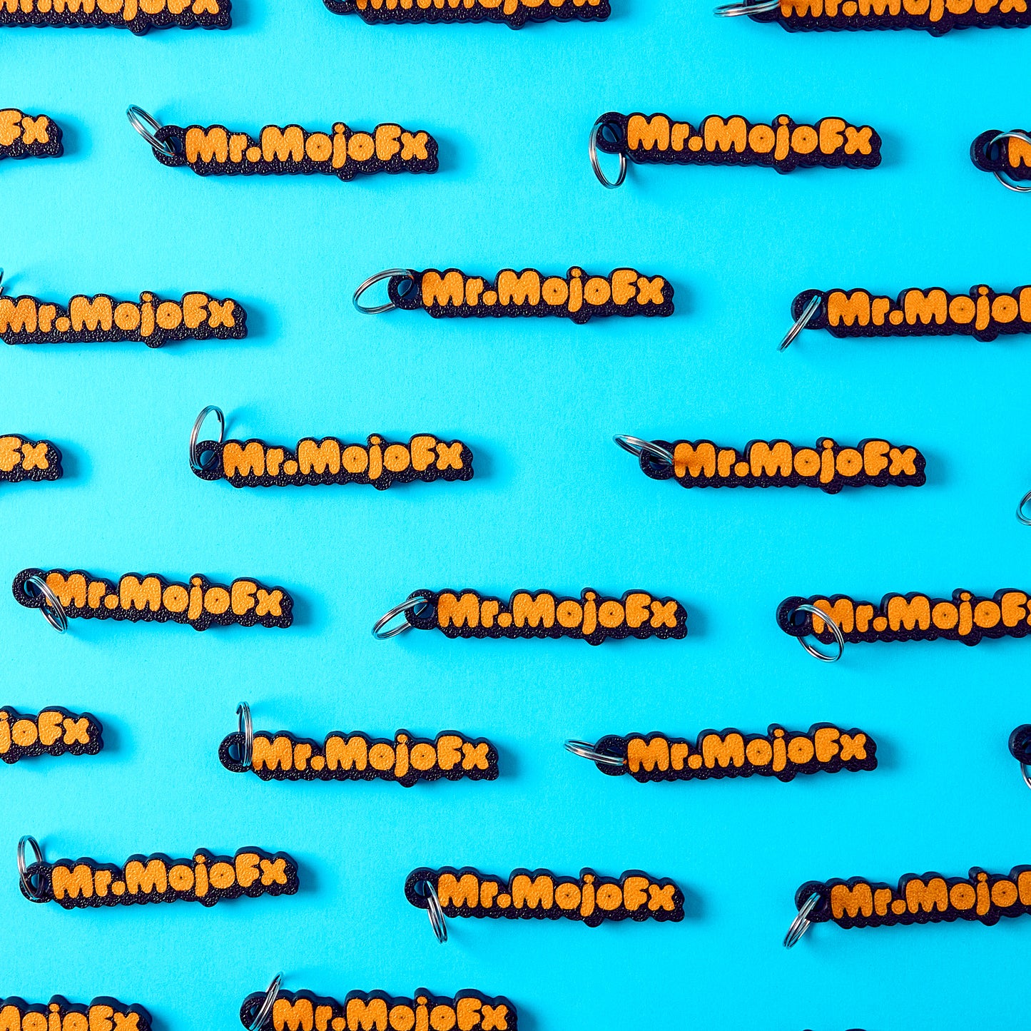 Mr.MojoFx mini key fobs — branded repeat pattern on teal background