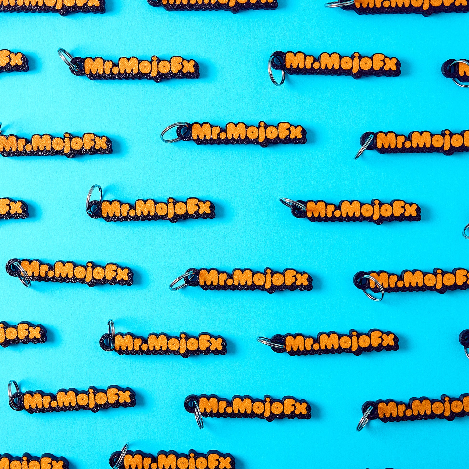 Mr.MojoFx mini key fobs — branded repeat pattern on teal background