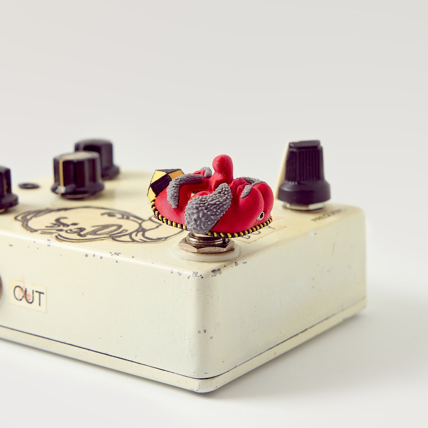 Tengu Topper — Japanese long-nose demon mask installed on vintage cream DirtyBoy effects pedal low angle showing topper height and footswitch fit