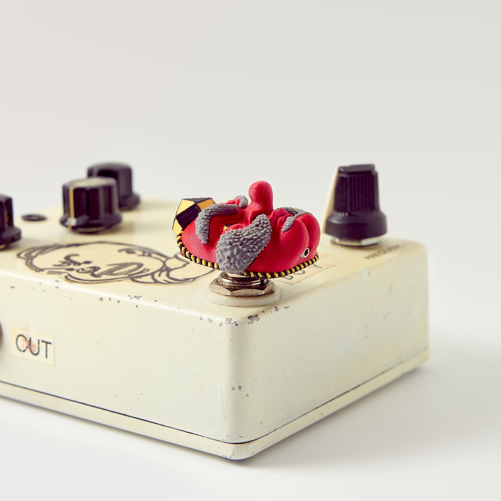 Tengu Topper — Japanese long-nose demon mask installed on vintage cream DirtyBoy effects pedal low angle showing topper height and footswitch fit